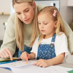 Mama próbuje zachęcić córkę do nauki, ale widać wyraźną niechęć do nauki na twarzy dziecka.