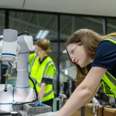 Uczennice technikum w kamizelkach odblaskowych pracują przy robocie. Edukacja domowa technikum w praktyce.