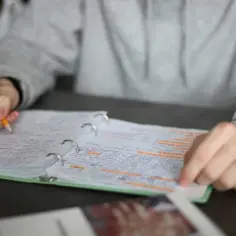Ręka z ołówkiem pisze w zeszycie, dopuszczając to 2 czy 3 razy.