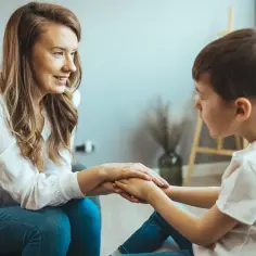 Terapeuta wspiera dziecko, którego przyszłość może być zagrożona niedostosowaniem społecznym. Dłoń w dłoń, budują zaufanie.