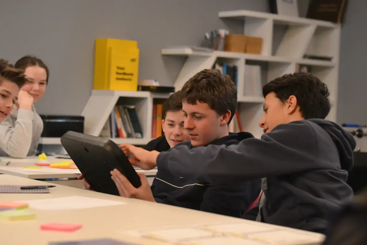 Uczniowie podczas zajęć, II etap edukacyjny, wspólnie pracują przy tablecie.