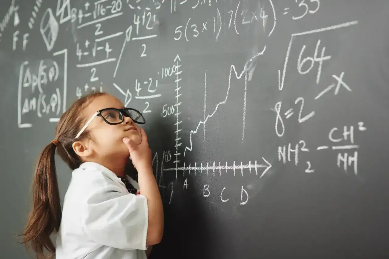 Mała dziewczynka w okularach zamyślona nad skomplikowanymi wzorami matematycznymi. Wygląda na to, że ma problemy z matematyką.